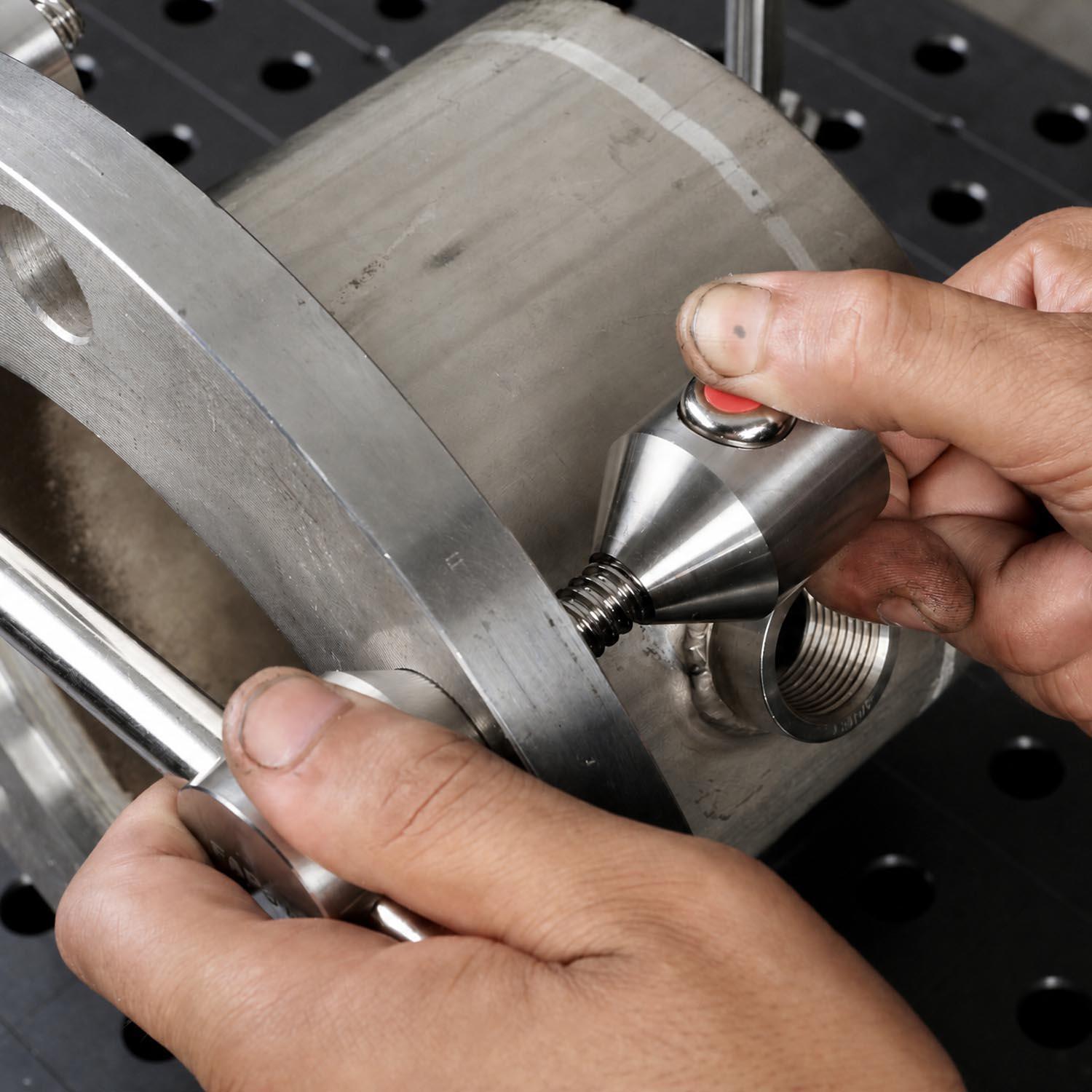 Person measuring a metal part with a caliper tool.