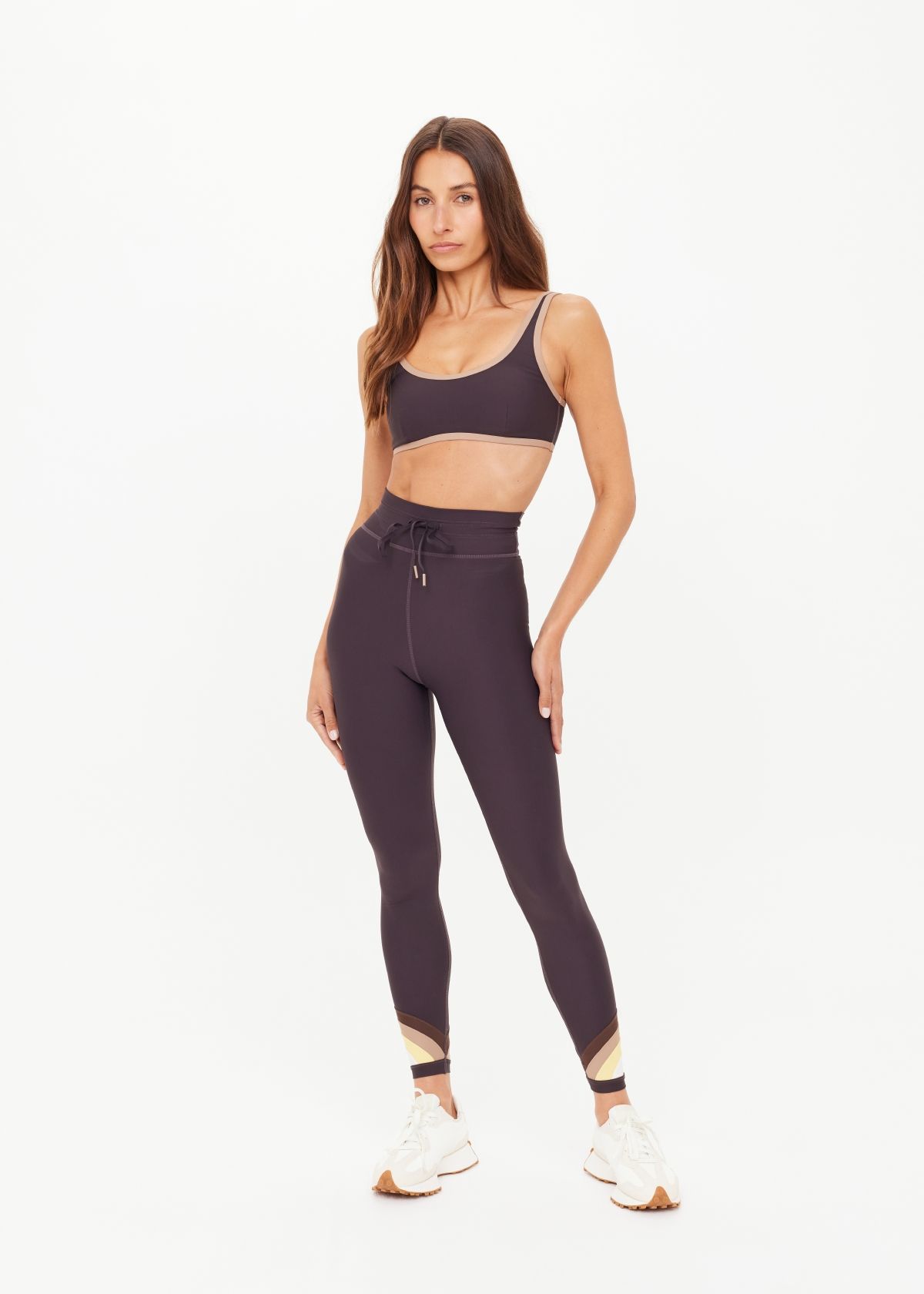 Woman in athletic wear posing against a plain background.