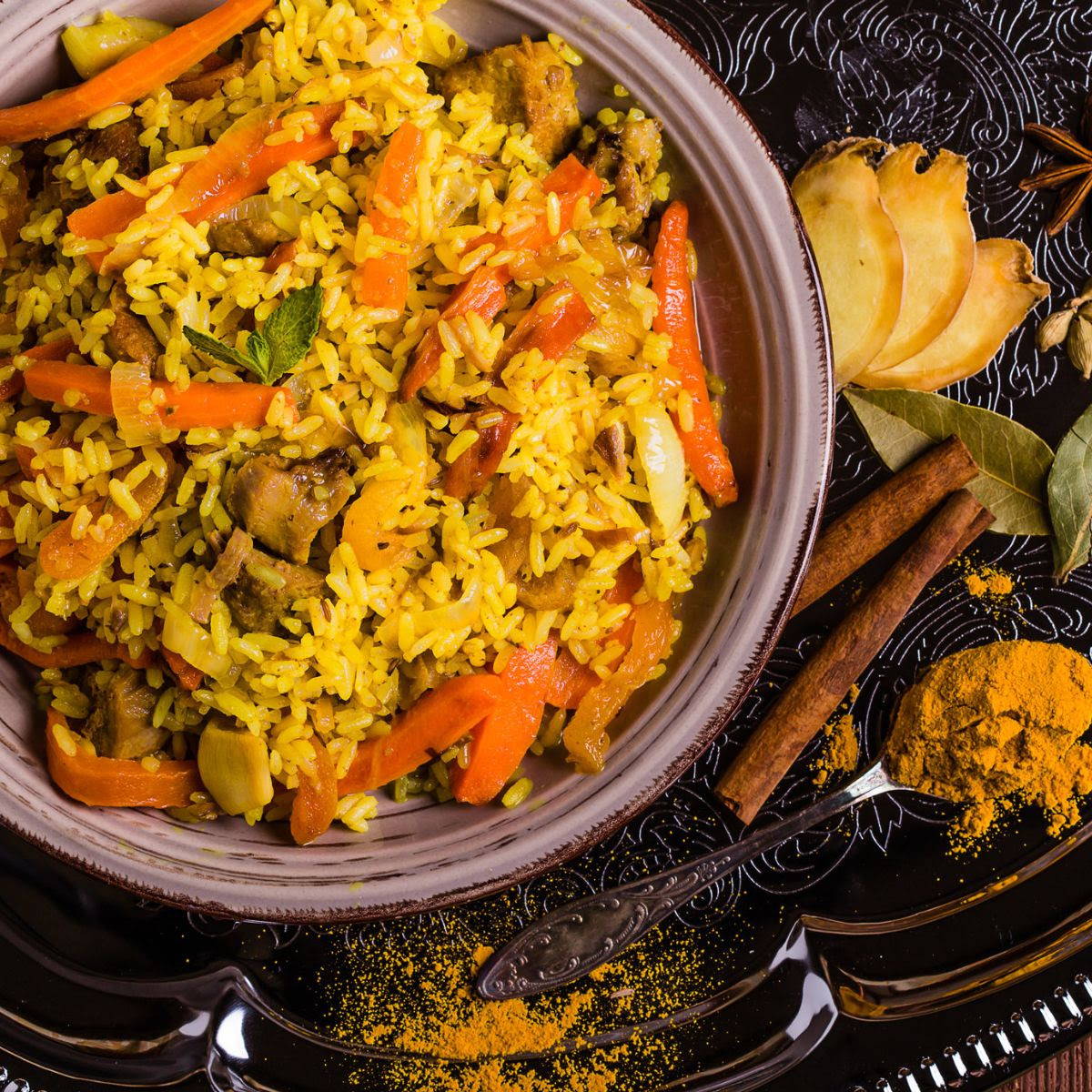 carrots and yellow rice in bowl with bay leaf and spices next to the bowl