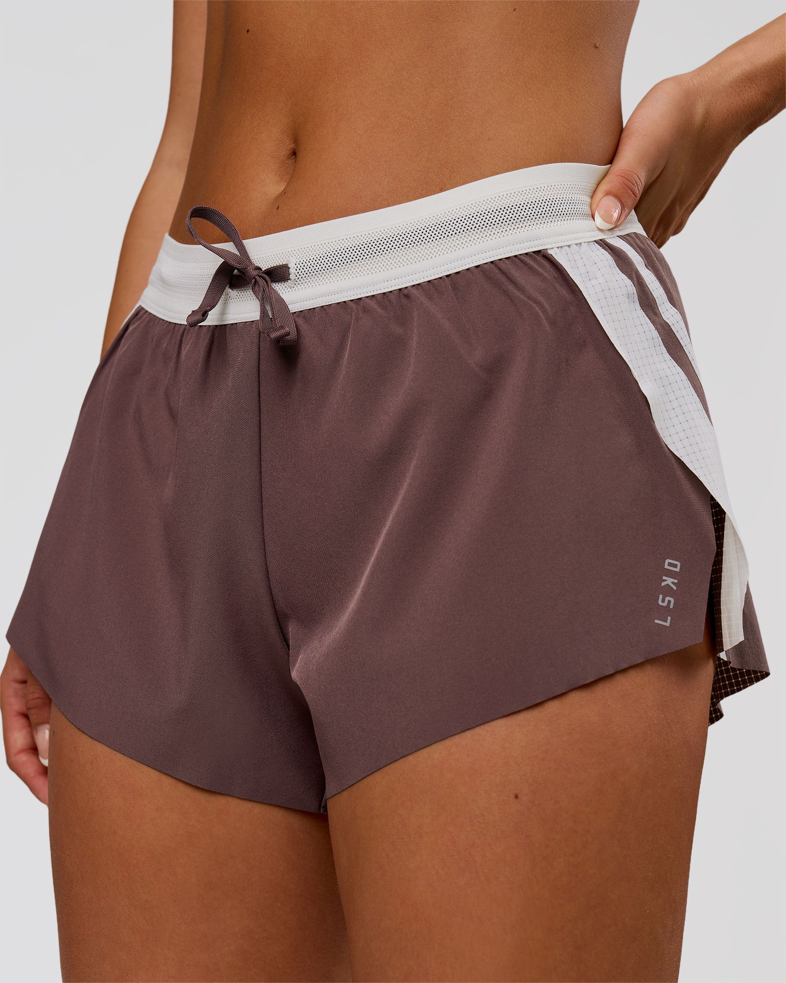 Woman wearing brown athletic shorts with a white waistband and side accents.