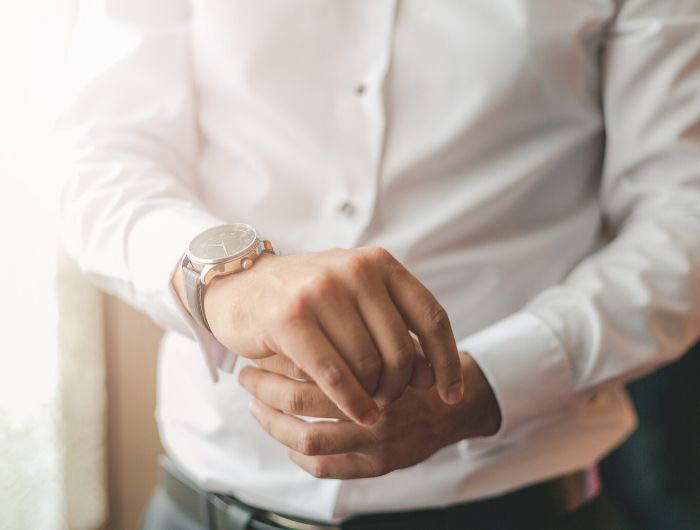 Man putting watch on with formal attire