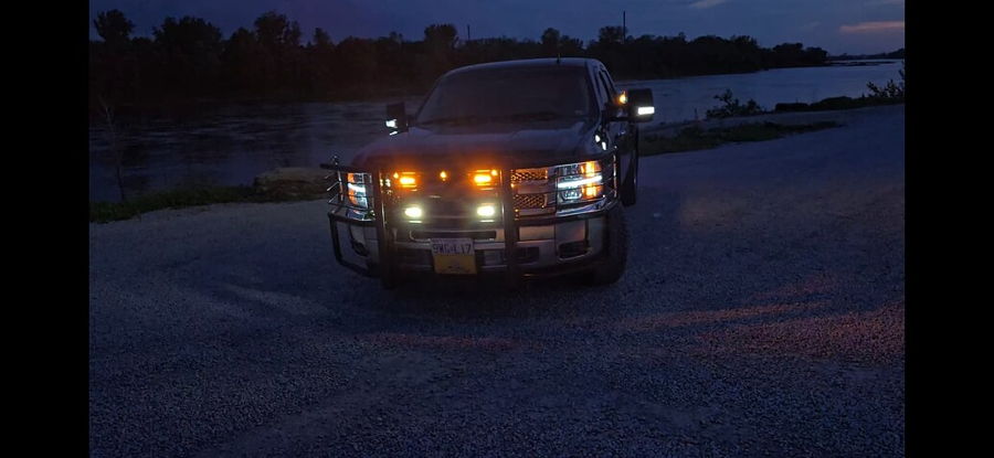 Front view Hunter's 2012 Chevy Silverado at dusk with headlights LED accents and auxiliary lights on brush guard by river gallery photo 2