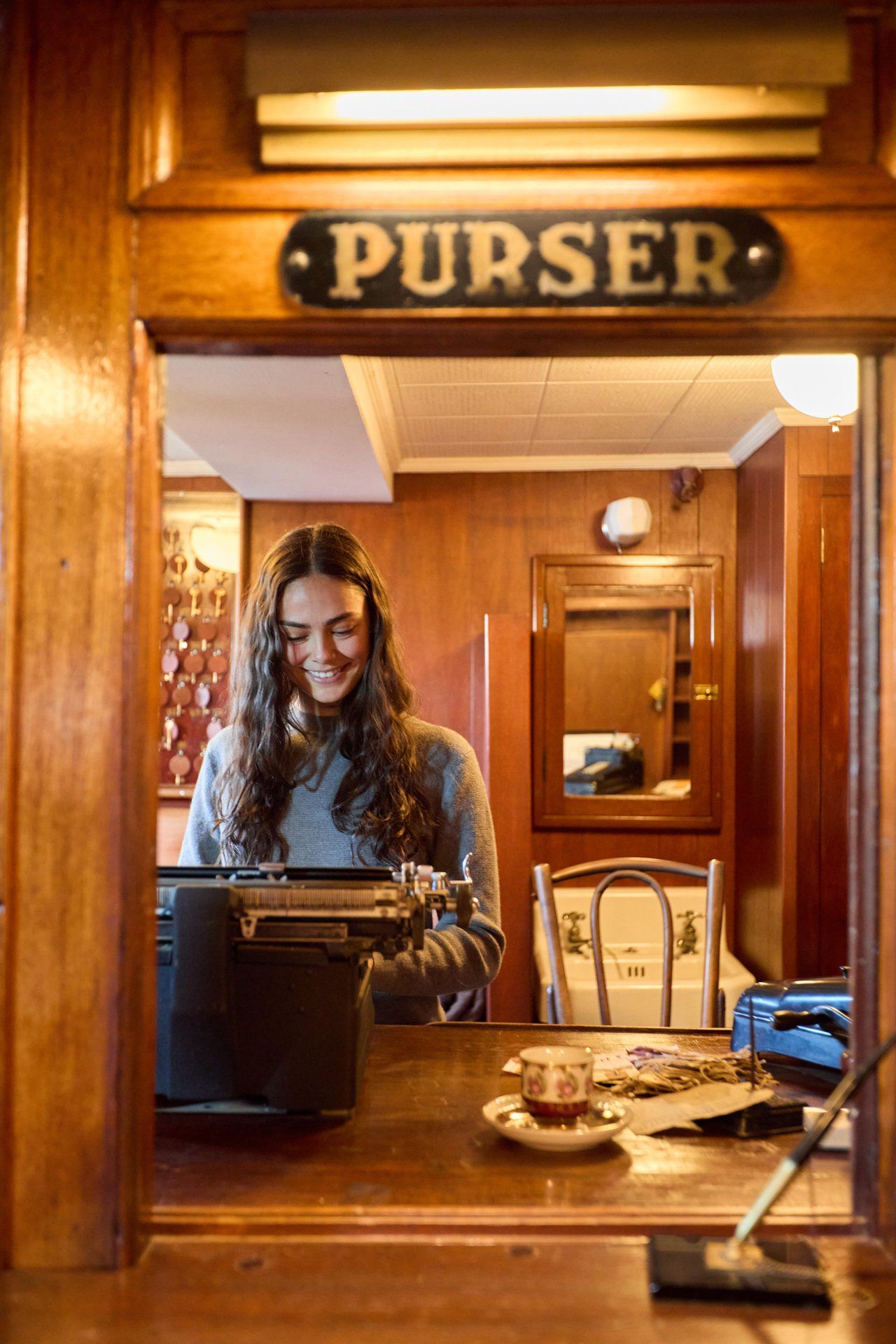 Person using a typewriter at a wooden purser's desk.