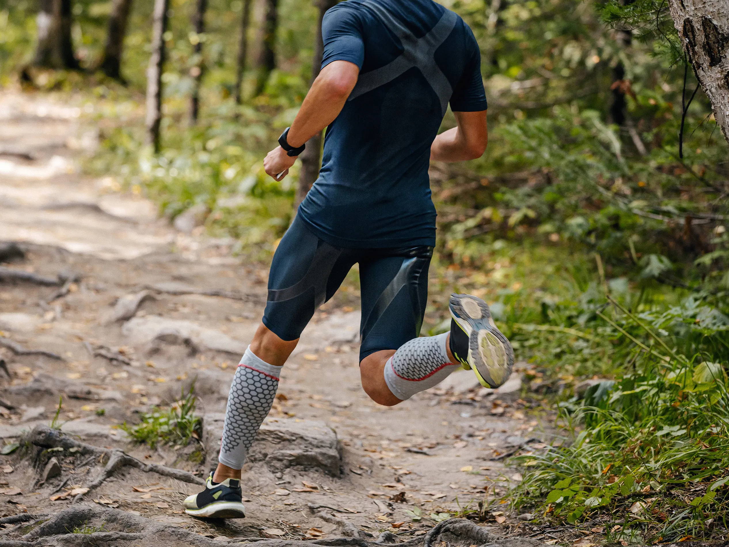 Man running on trail in compression sleeves