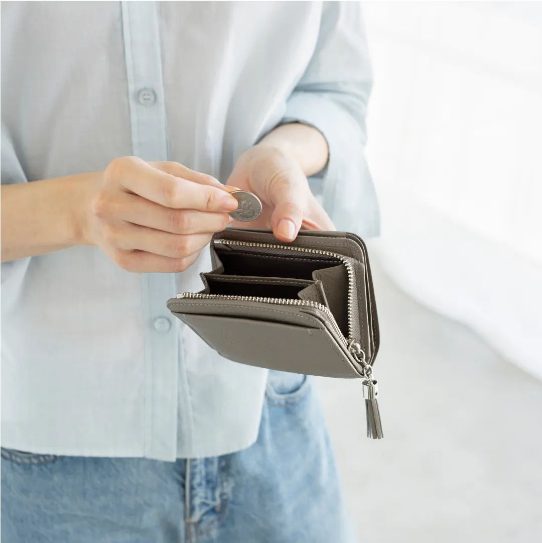 A person holding a gray wallet and inserting a coin.