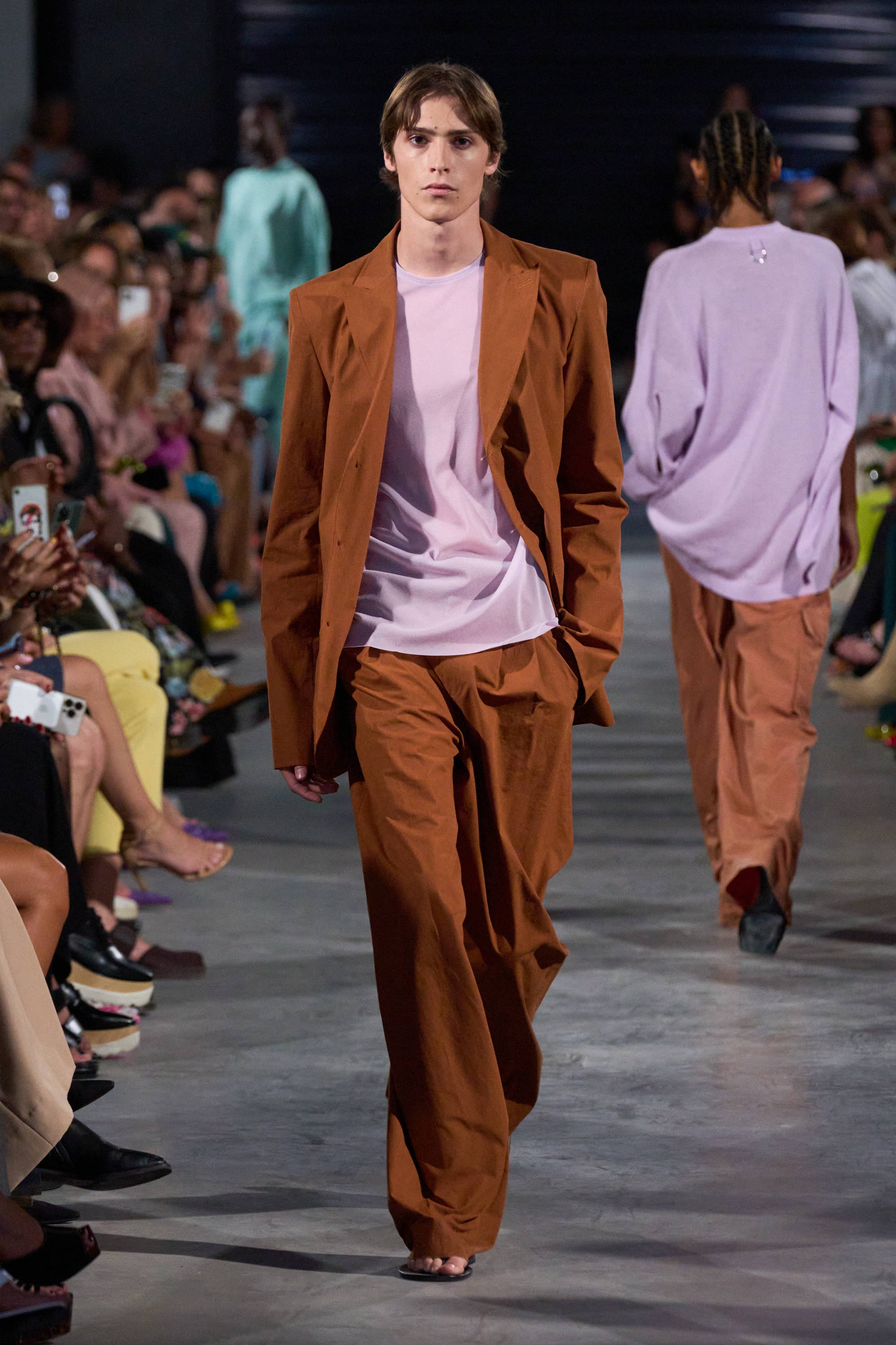 Model on a runway wearing suit and sheer top
