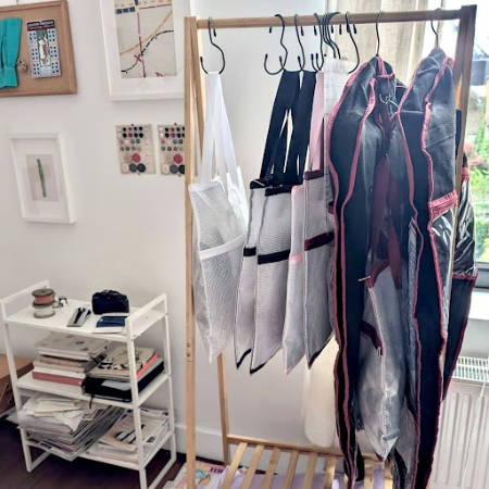 a rack in a sewing room with project bags and garment project bags for project storage