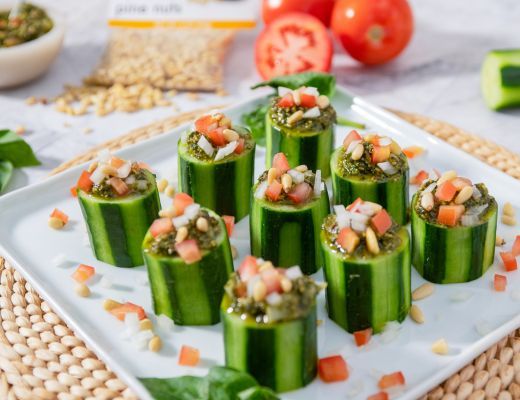 Cucumber cups filled with vegetables and herbs on a white plate.