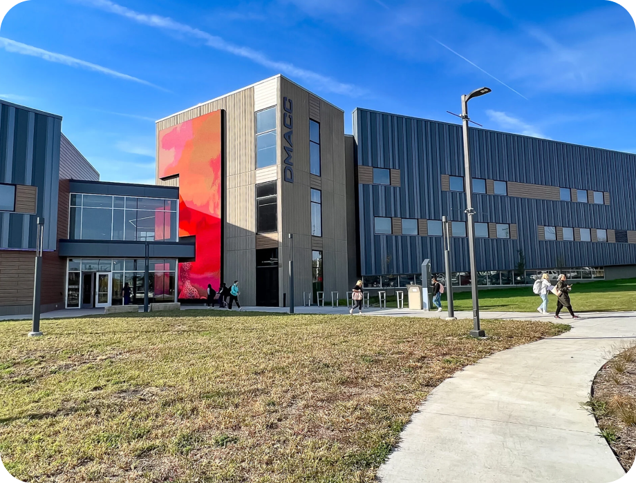 Modern building with colorful mural and people walking on a path.