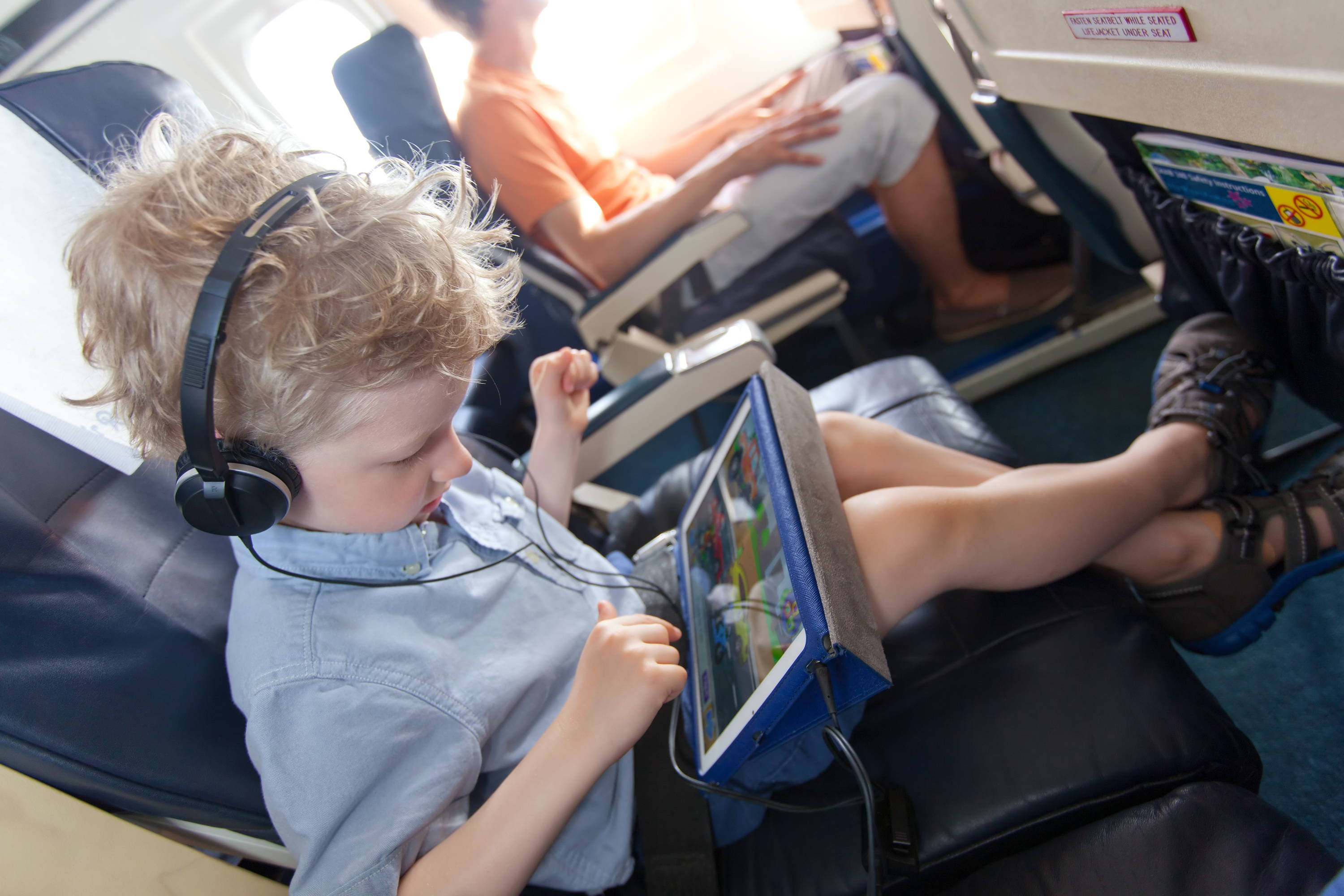 kid playing on an electronic device while on the plane