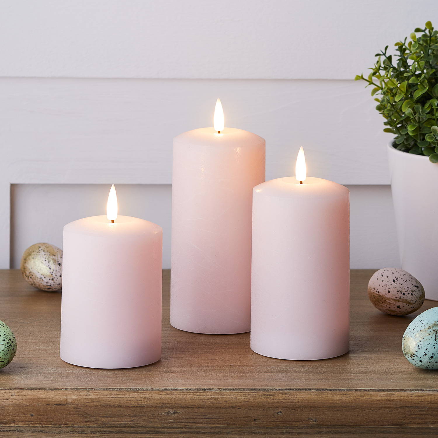 3 Bougies Piliers TruGlow® Rose Pastel sur une table. 