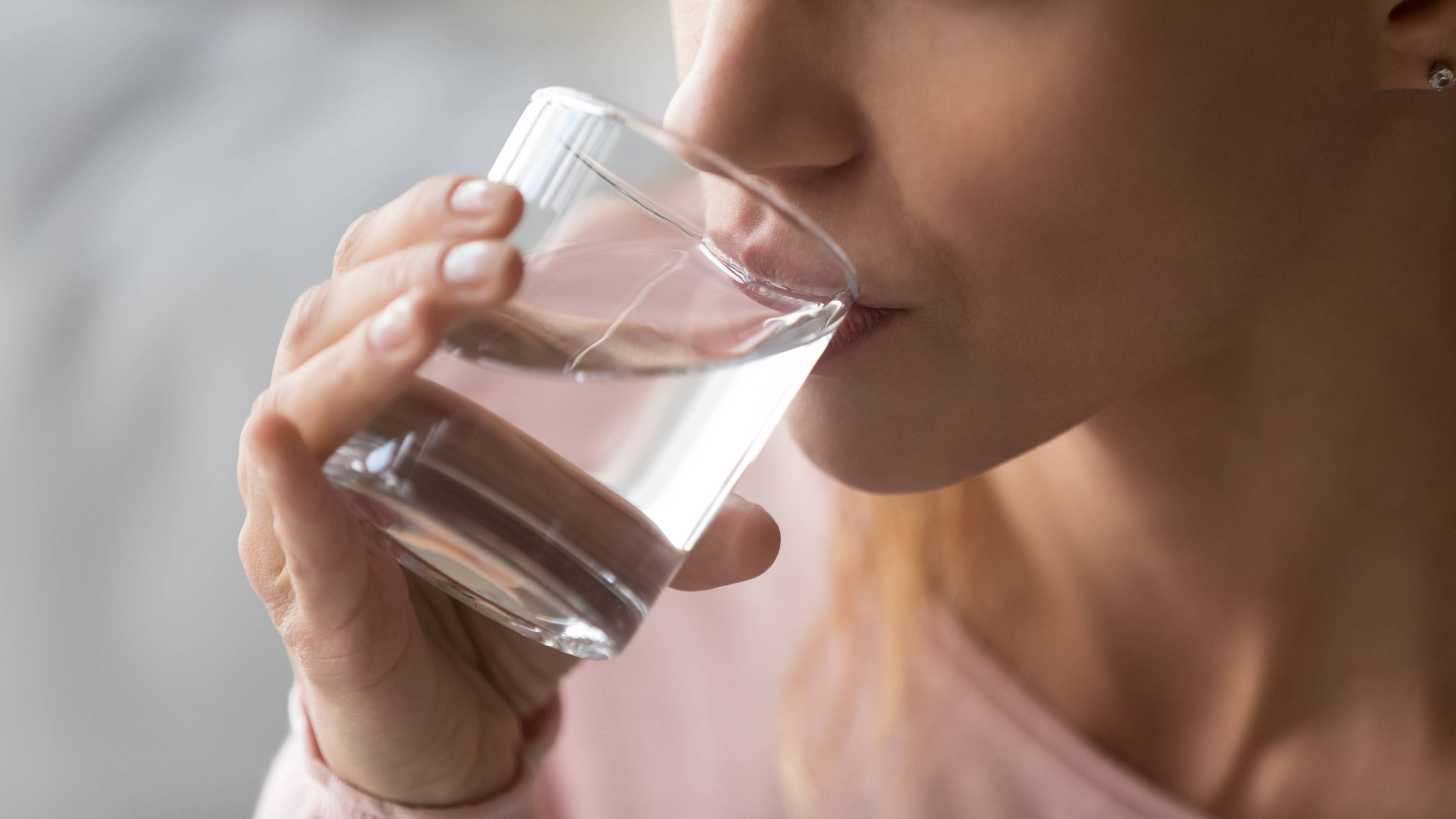 Close-up cropped image of woman sipping glass of water.