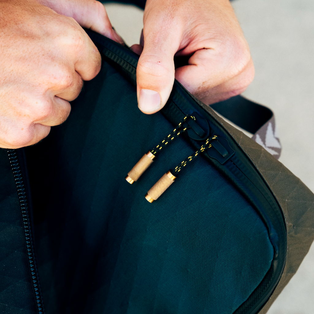 Person opening a bag with zipper pulls visible.