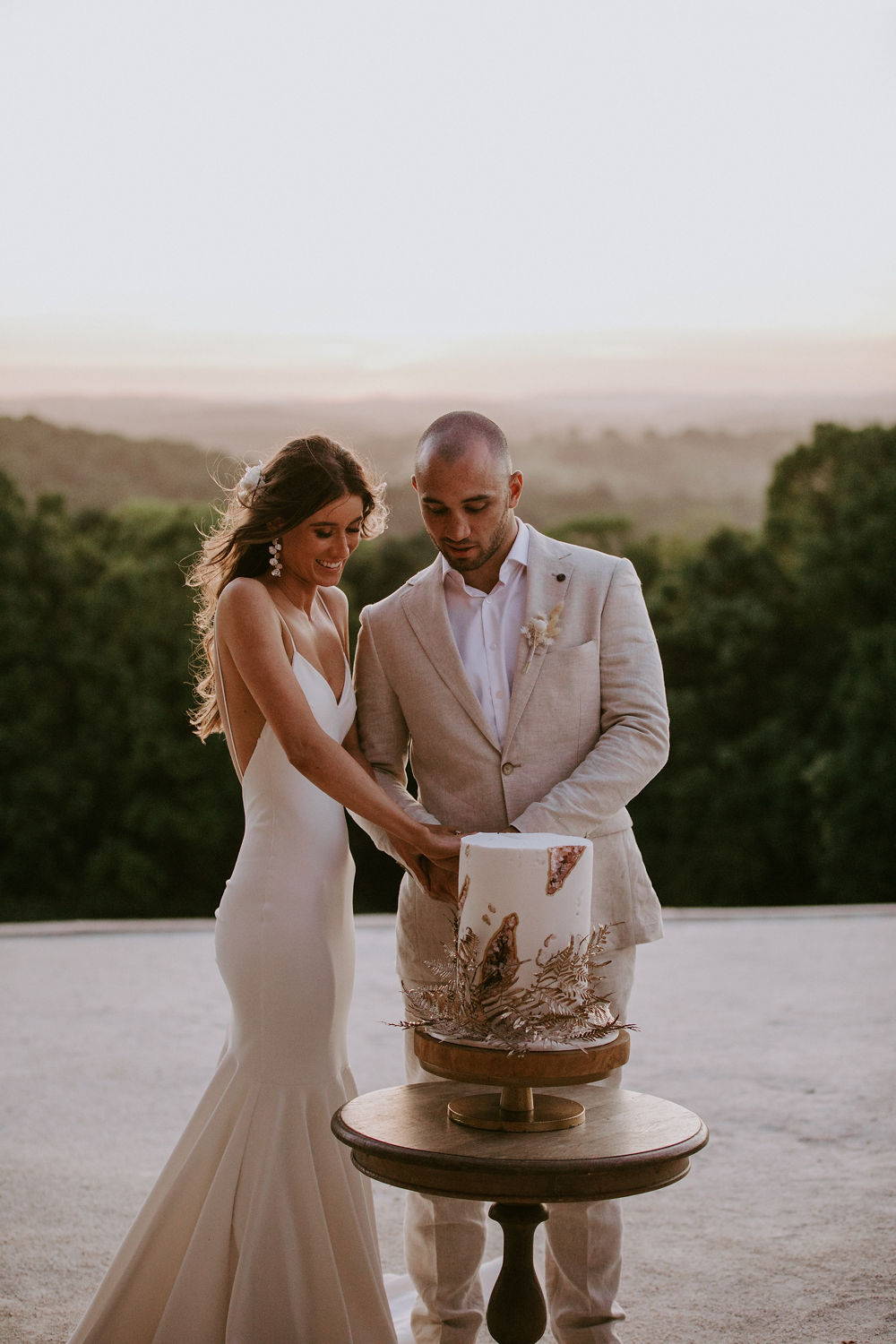 Grace Loves Lace bride wearing the Clo Crepe gown curring a cake with her groom