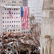 Destruction site with American flag and debris from collapsed buildings.