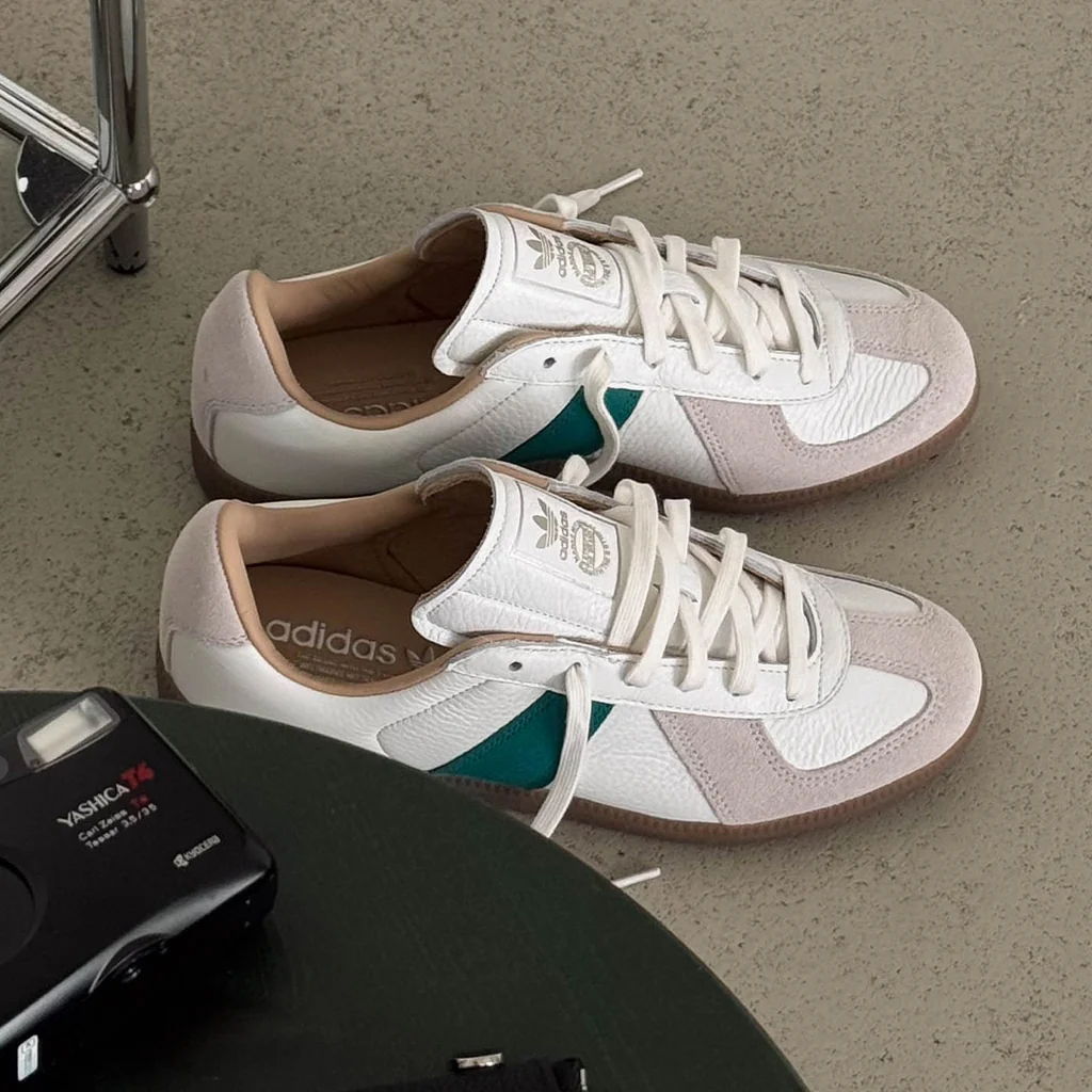 A pair of white and teal sneakers on a concrete surface.