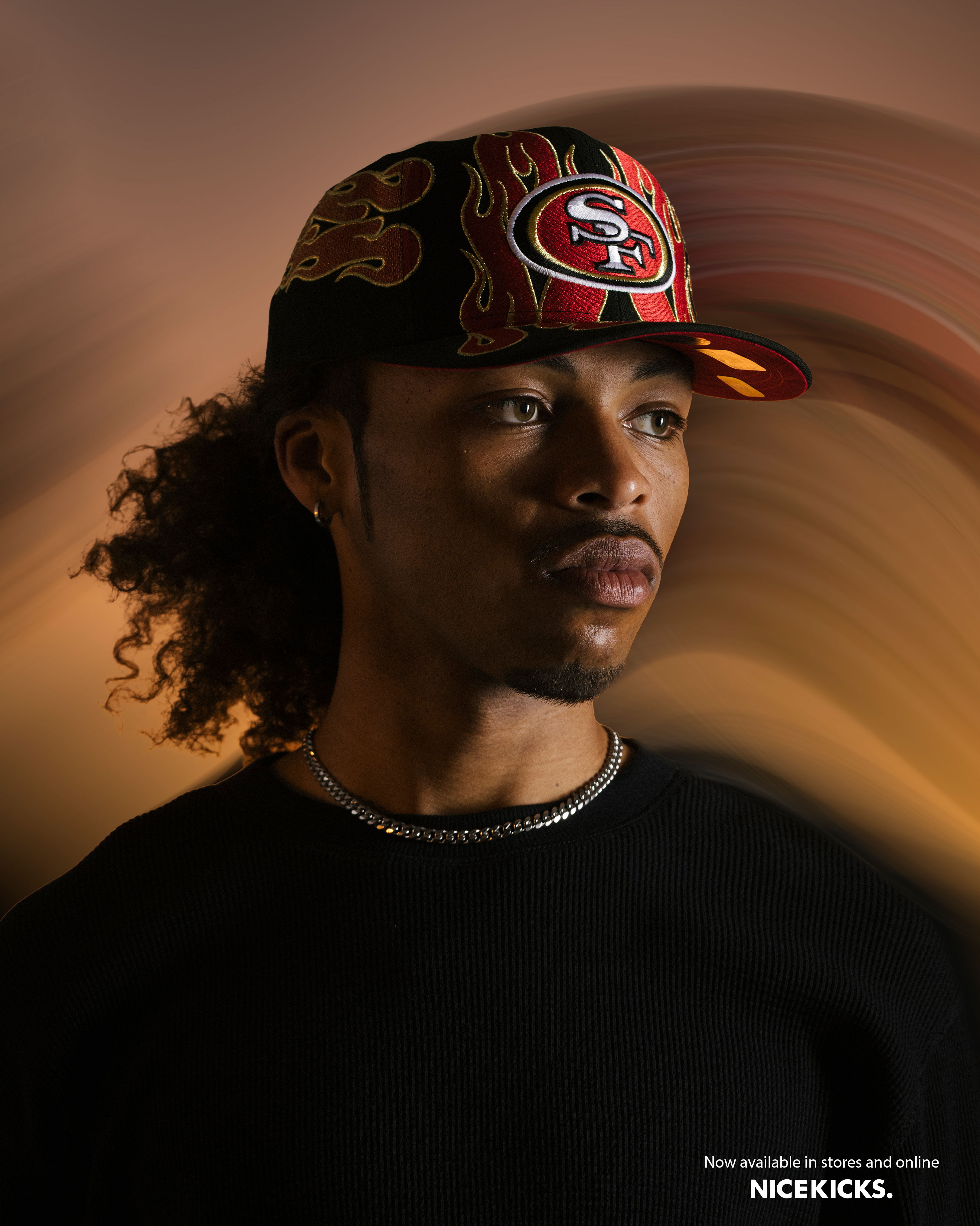 A person wearing a cap with a fiery design against a blurred background.