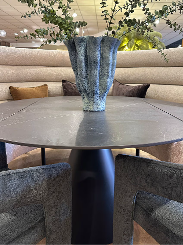 Round black stone table and curved boucle dining bench