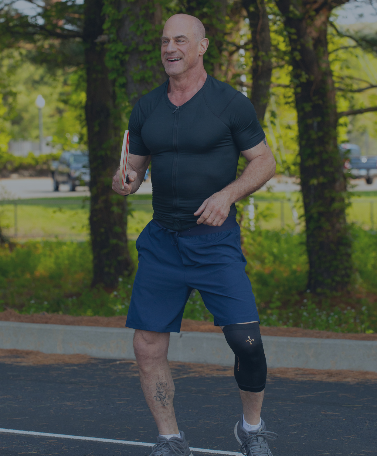 Christopher Meloni playing pickleball wearing Tommie Copper compression