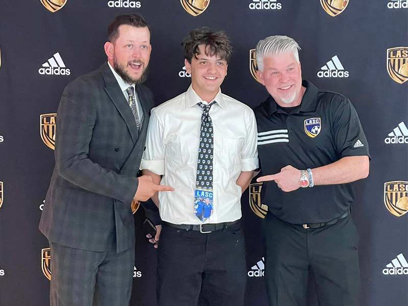 Teen wearing a custom soccer tie with his couches at an awards ceremony