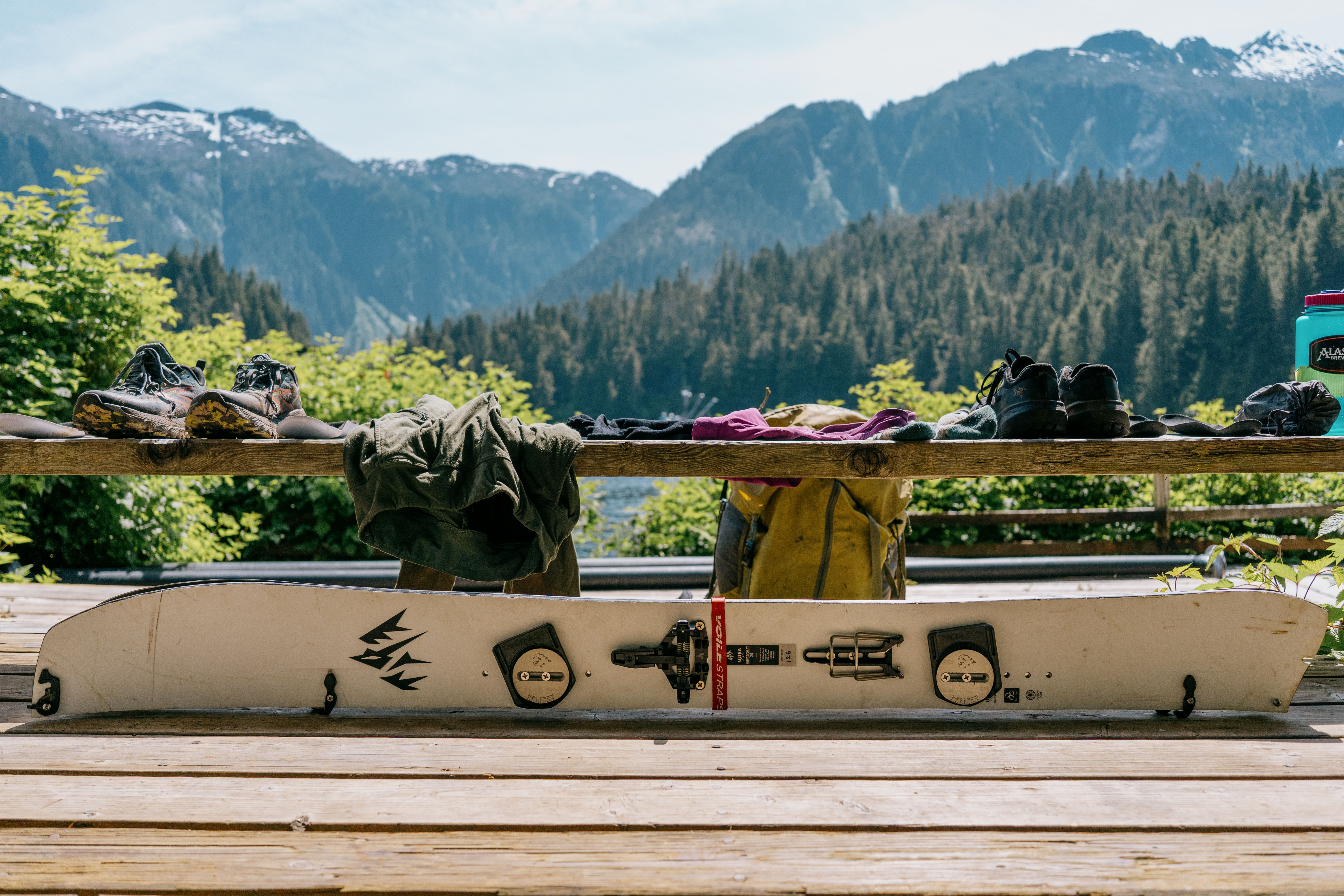 A splitboard resting on a wooden table with mountains in the background.