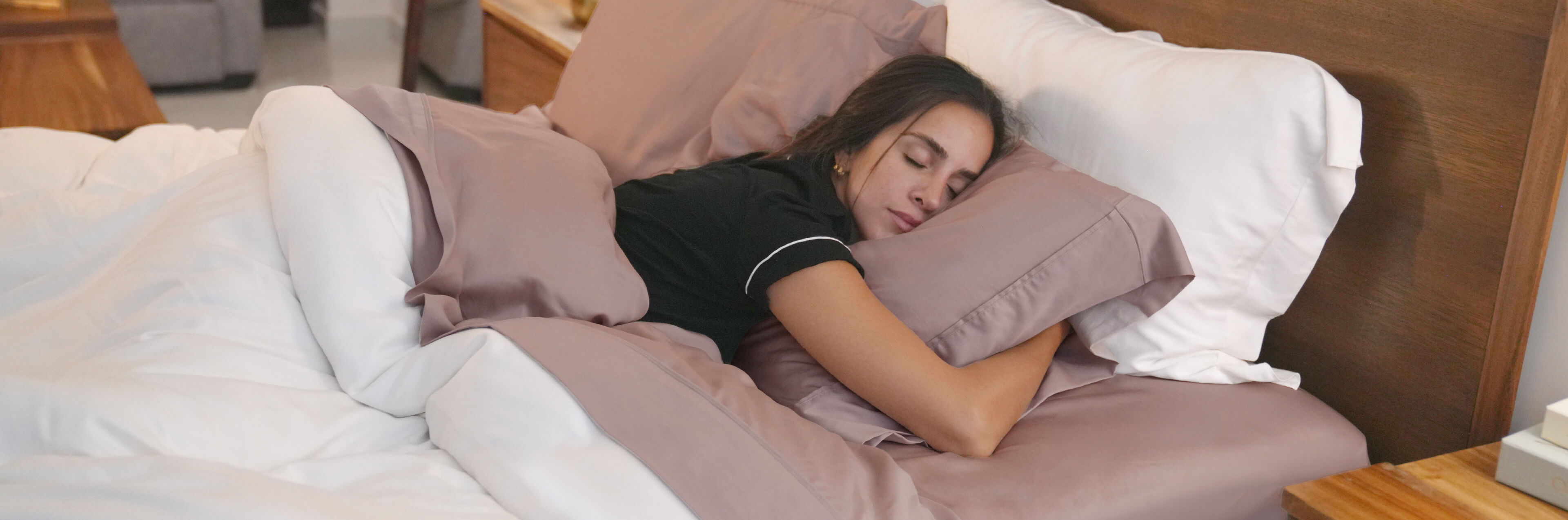 a woman lying on a bed with blush bamboo sheets and a white duvet