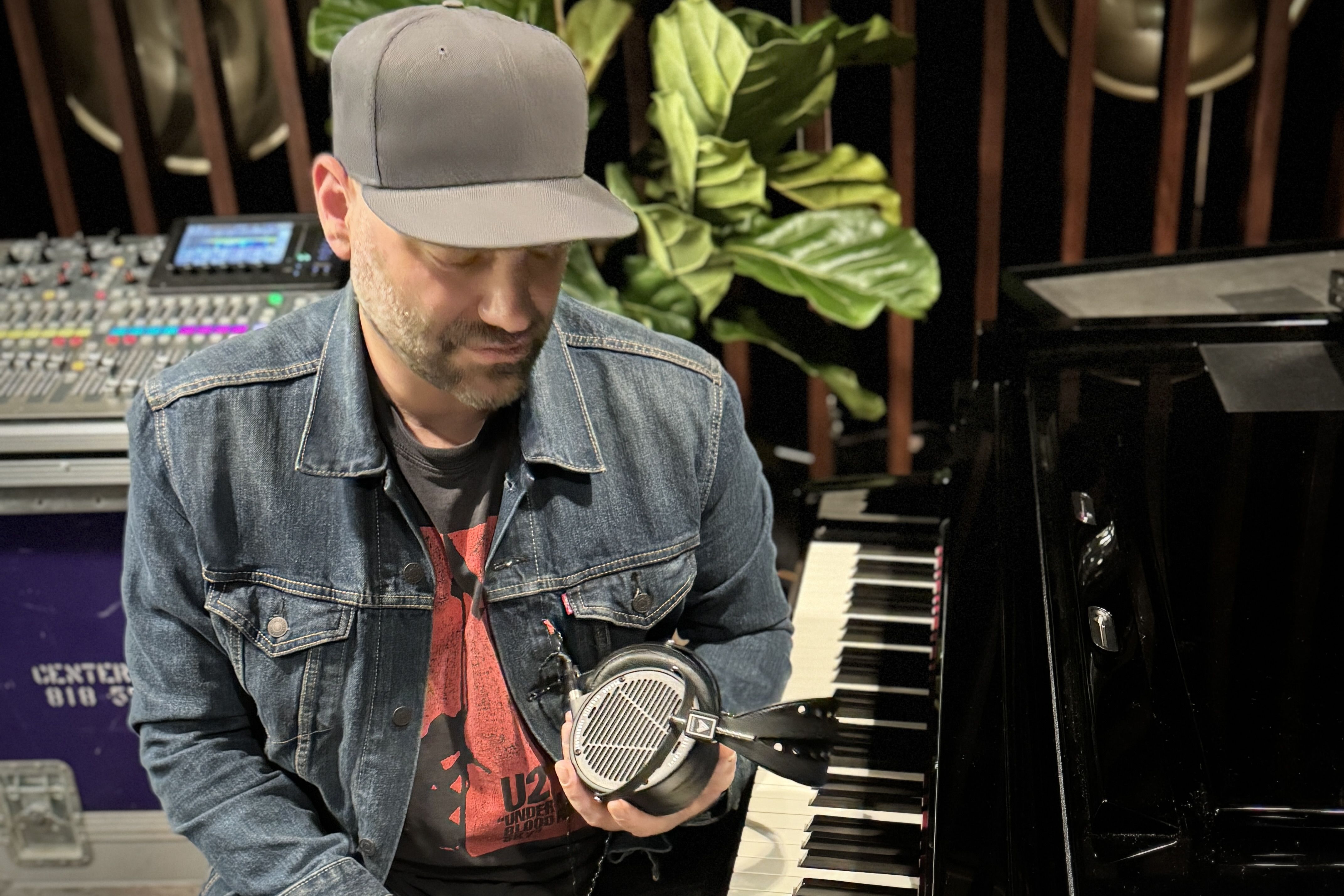Scott Simmons holding Audeze LCD-X headphones next to a piano