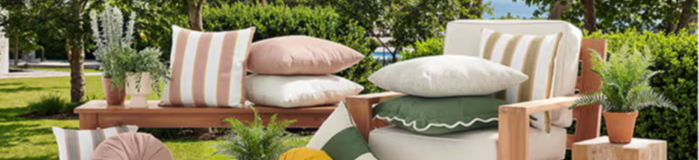 Outdoor seating area with cushions, plants, and wooden furniture.