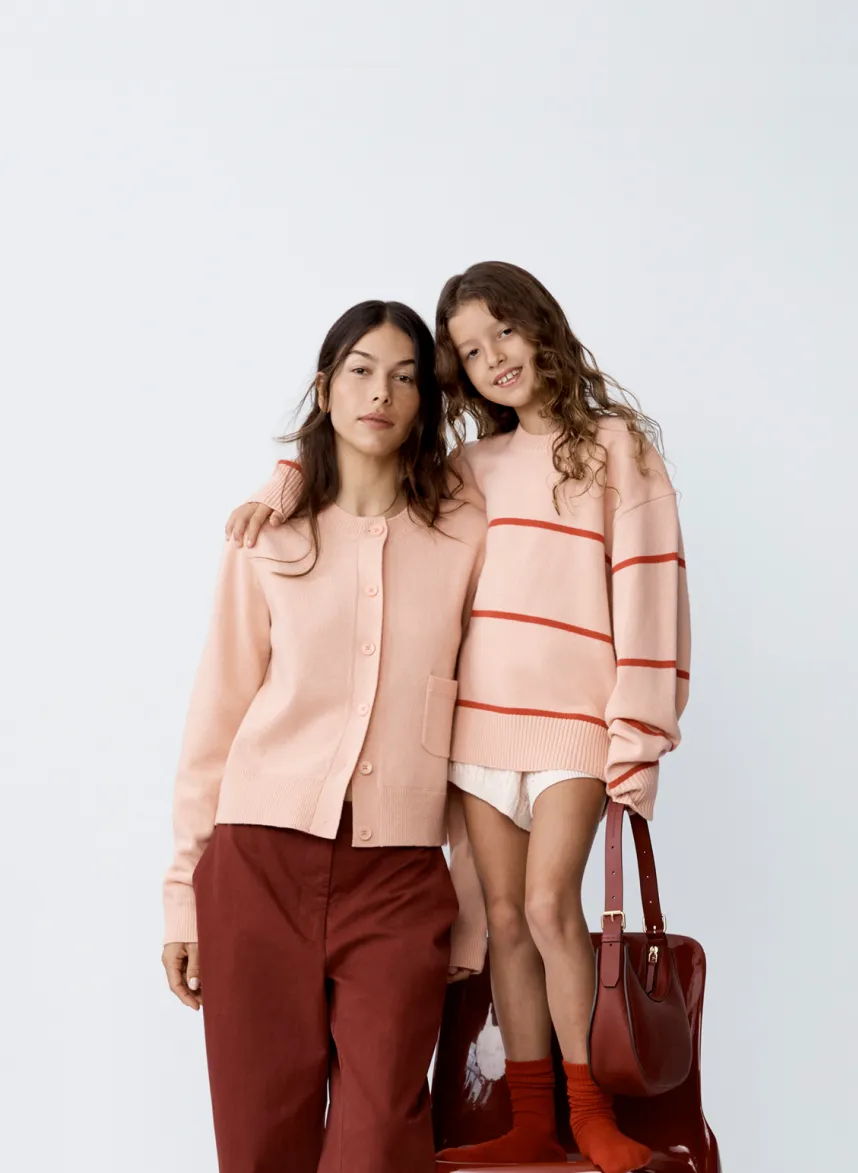 Woman and girl in matching outfits, posing together with a handbag.