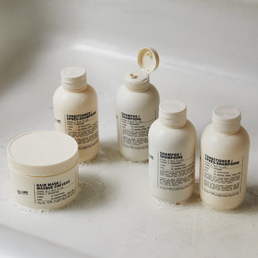 Five bottles and one jar of skincare products on a white surface.