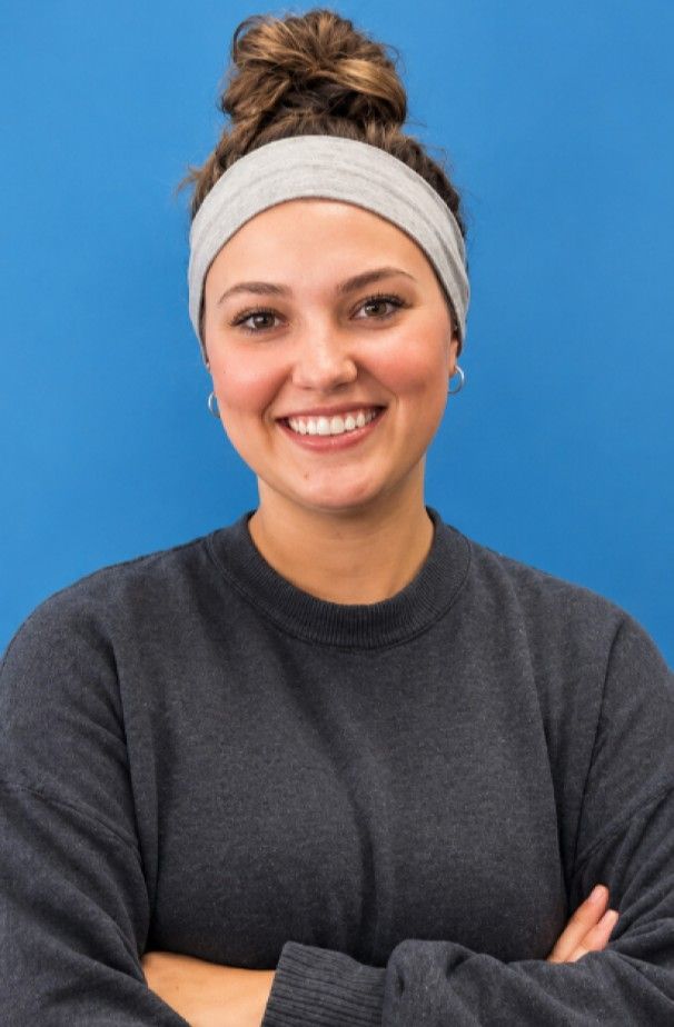 Smiling young woman with a headband against a blue background.
