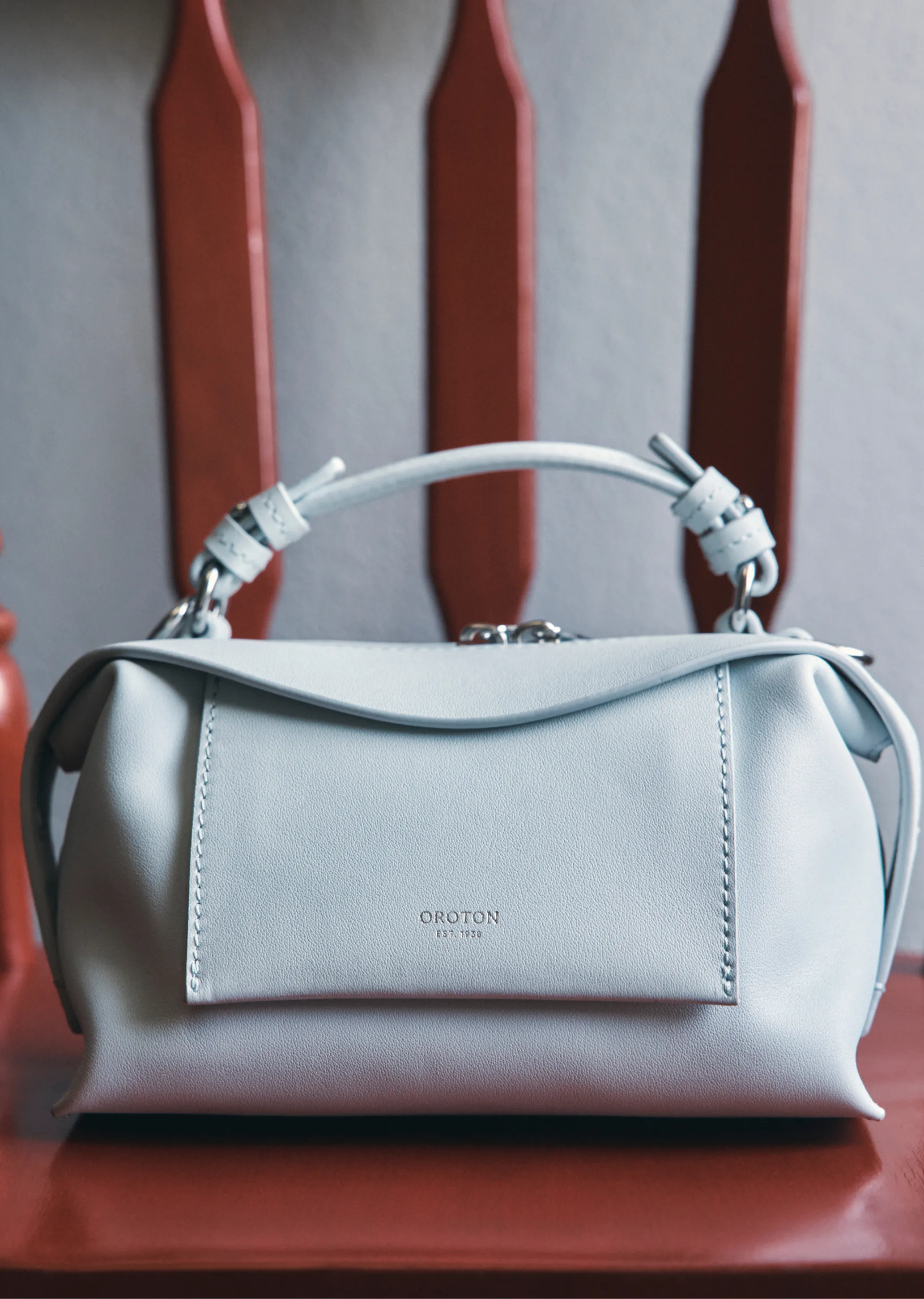 Light blue leather handbag on a red wooden surface.