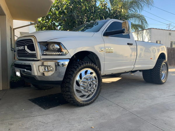 White lifted Ram 3500 Heavy Duty single cab dually with chrome wheels and Bandit M/T tires on driveway