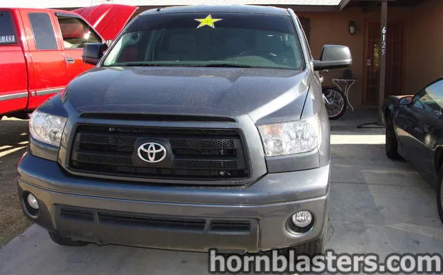Front-facing dark gray Cody's 2010 Toyota Tundra pickup black mesh grille chrome Toyota emblem fog lights concrete driveway HornBlasters Shocker XL train horn featured customer install gallery photo 1