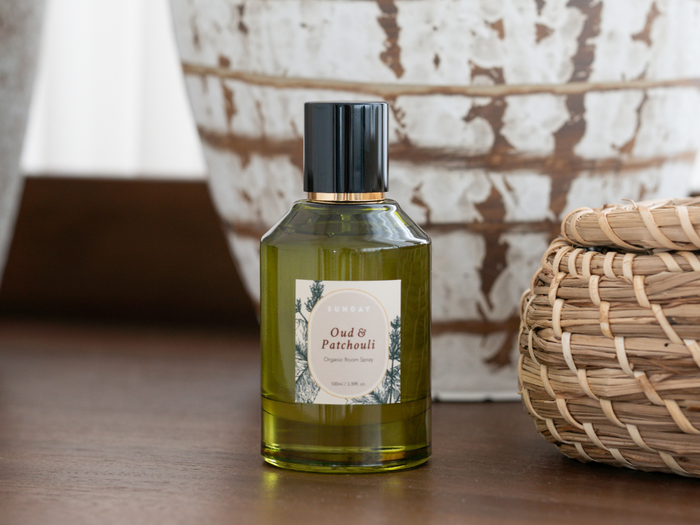 organic room spray in a bottle placed on a table next to a rattan basket