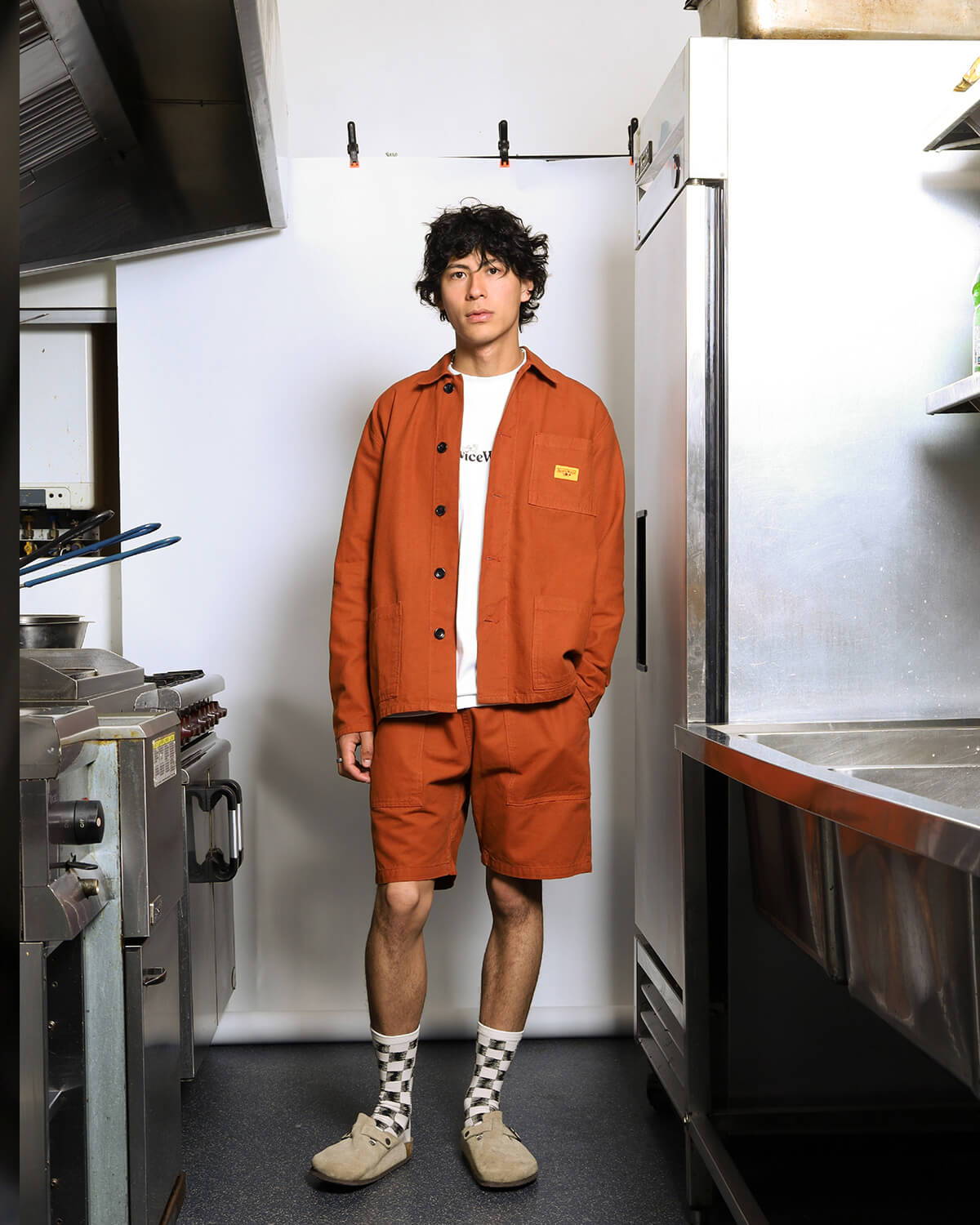 A look book image of a model wearing the Service Works Canvas Chef Shorts in Terracotta.