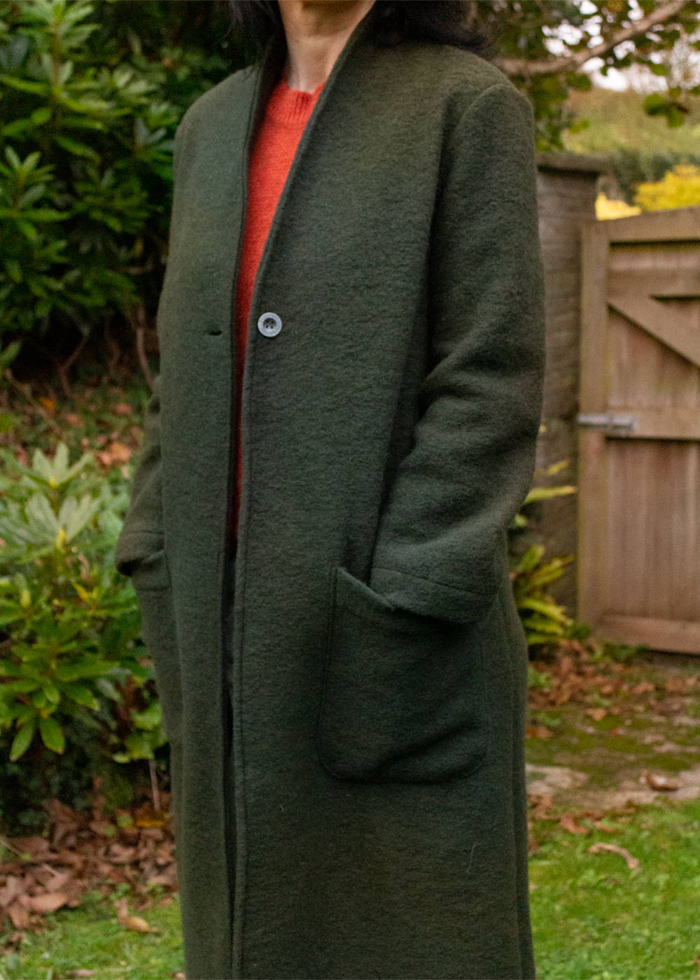 A model wearing a green woolen coat over a red jumper