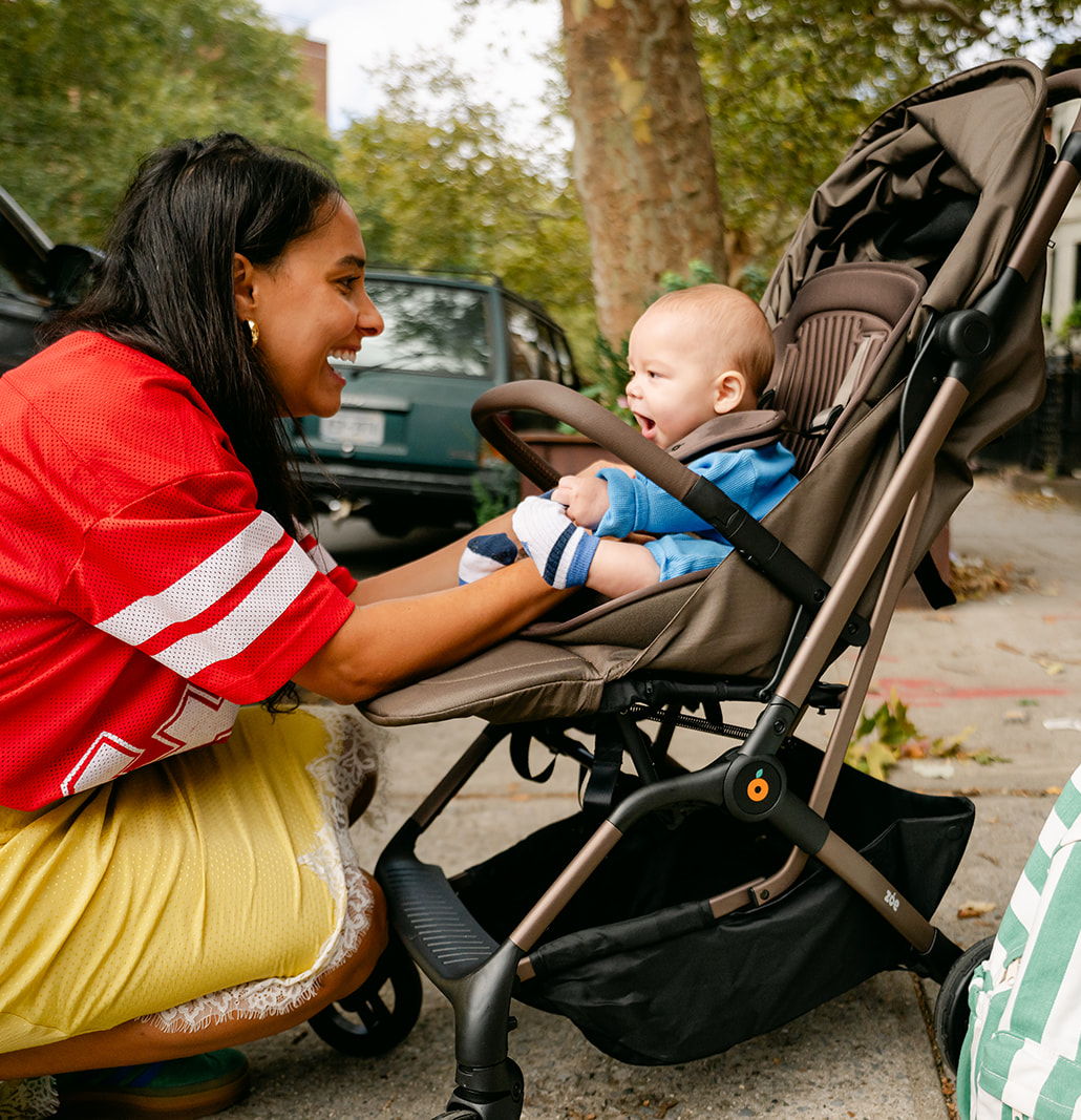 Woman interacting with a baby in a stroller outdoors.