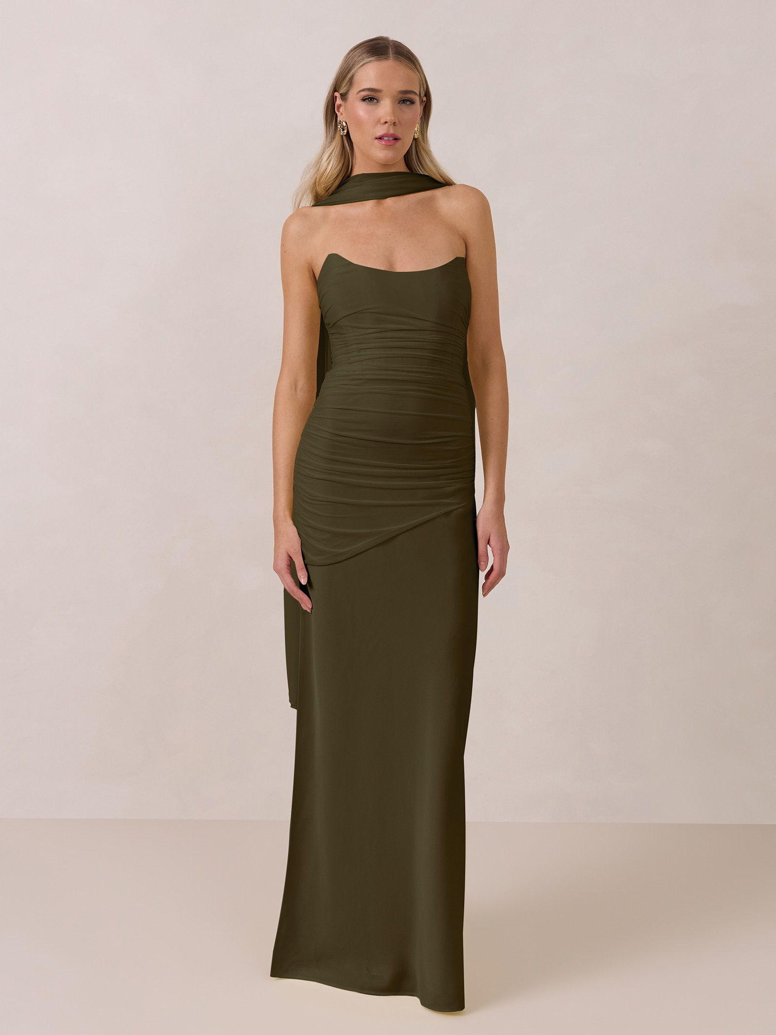 Woman in a fitted olive green dress, standing against a neutral background.