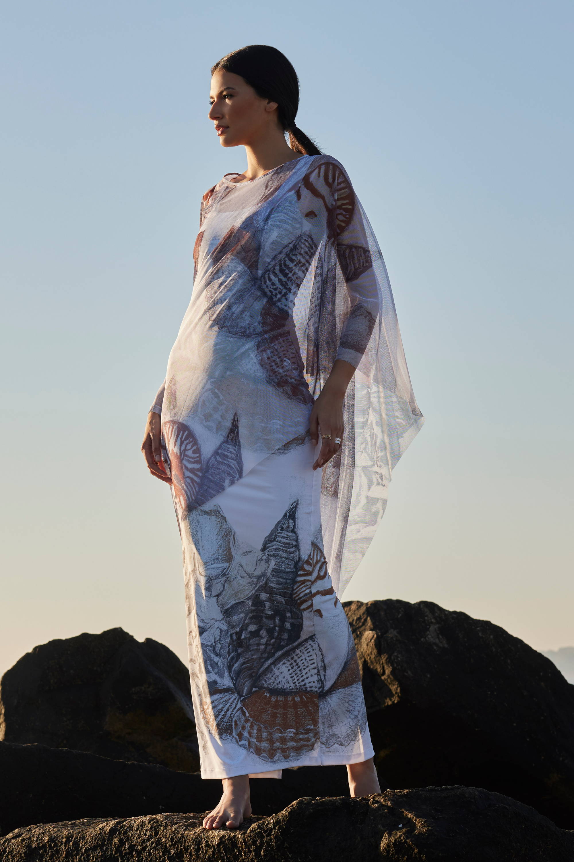Woman wearing brown and white mesh cover up kaftan over long stretch knit dress on the beach by Ala von Auersperg