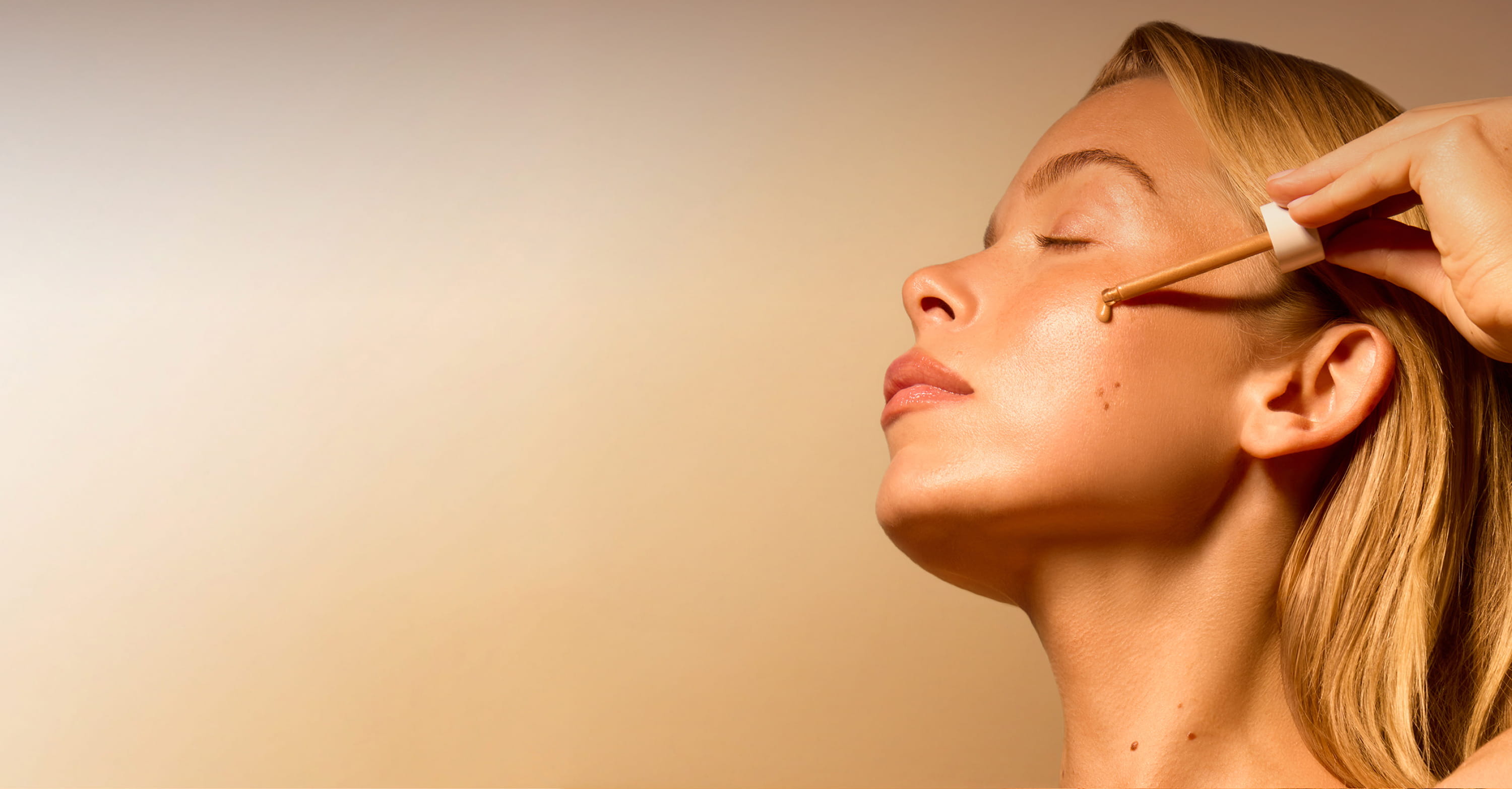 Woman applying makeup on her face against a neutral background.