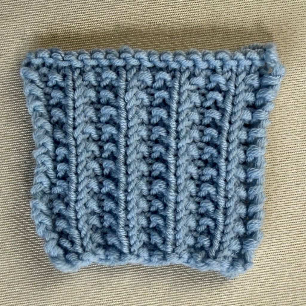 Eine Maschenprobe aus einem falschen Patentmuster in einem hellblauem Garn.