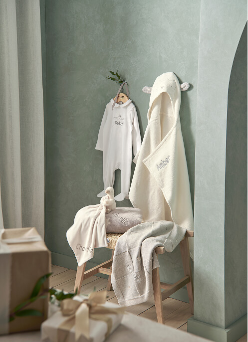 Cozy children's clothing and towels arranged on a chair against a green wall.