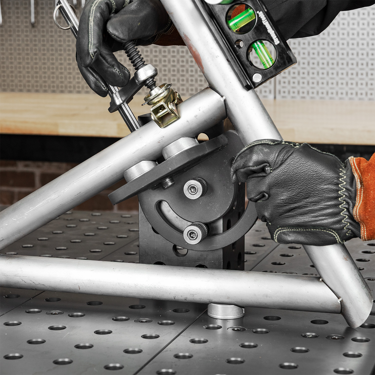 Person adjusting metal framework with tools on a workbench.