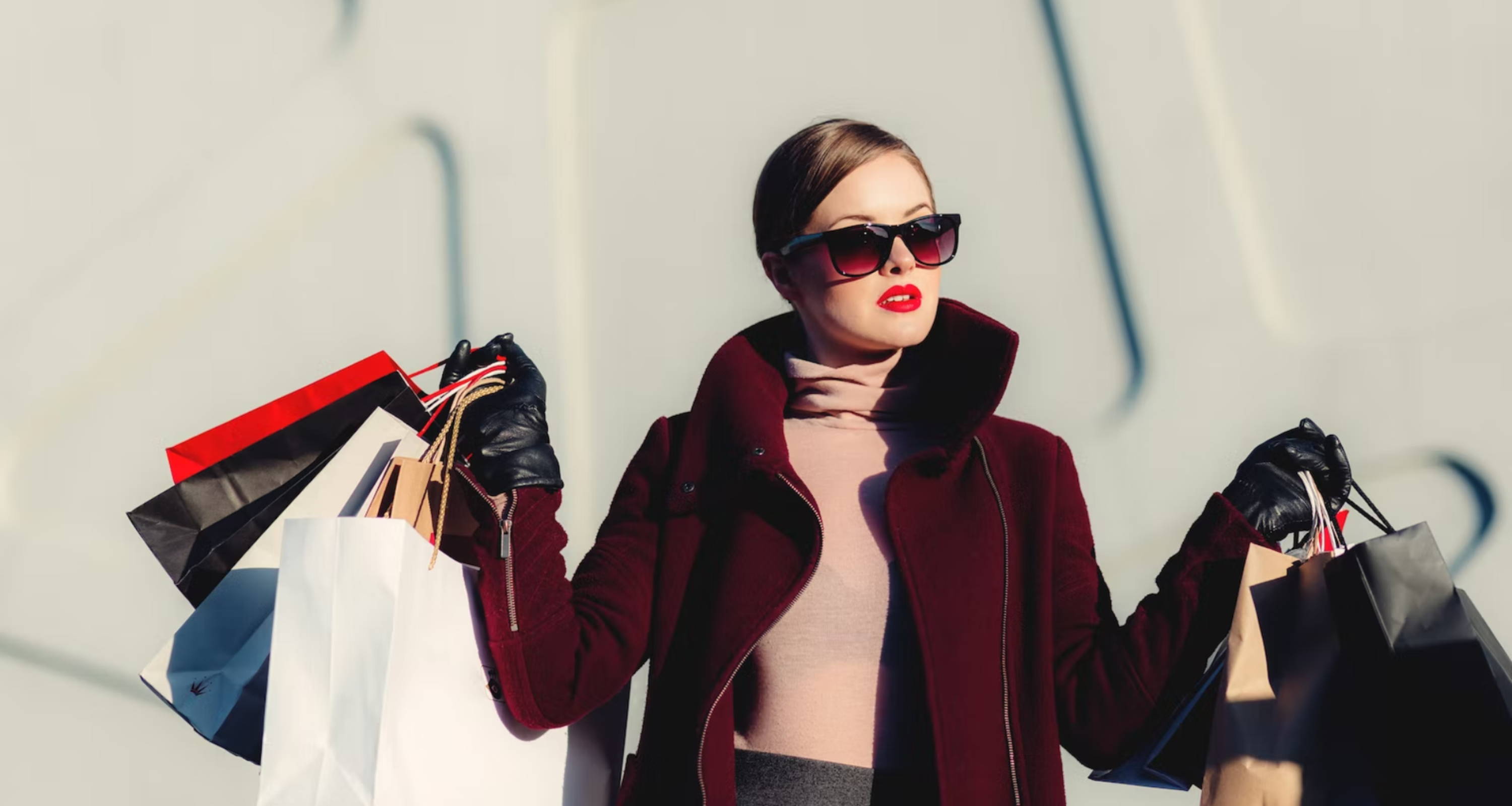 woman in sunglasses and red lipstick holding many shopping bags