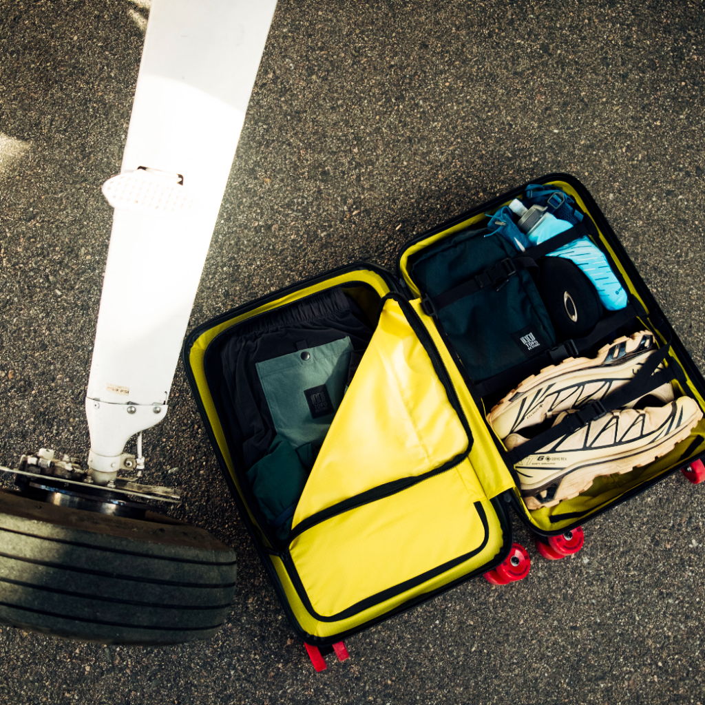 A suitcase with clothes next to an airplane wheel.