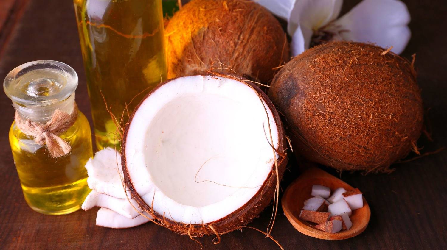 Coconuts and coconut oil on wooden table | The Best Uses For Coconut Oil For Health And Wellness | coconut oil uses | uses of coconut oil | Featured