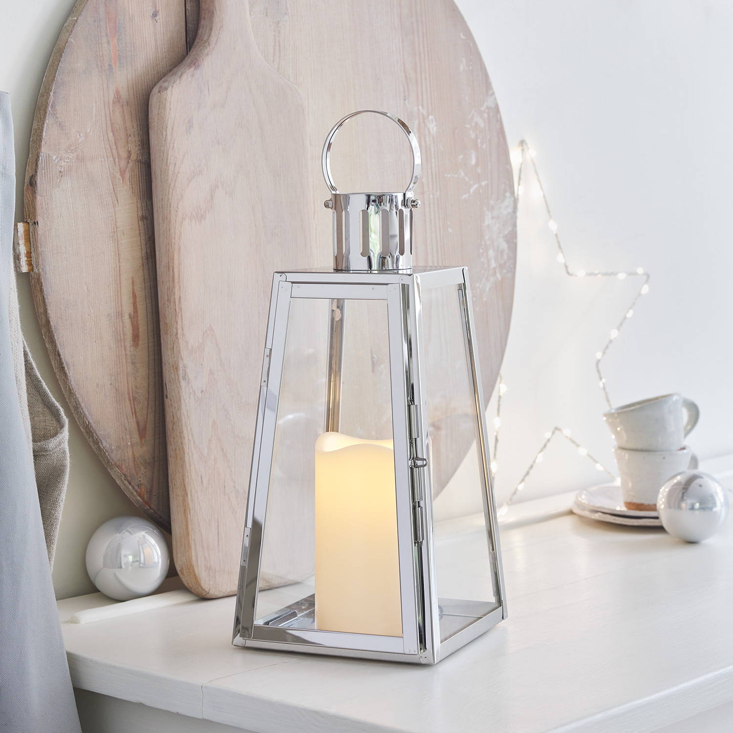A silver lantern with an LED candle inside on a kitchen surface with an osby star in the background.
