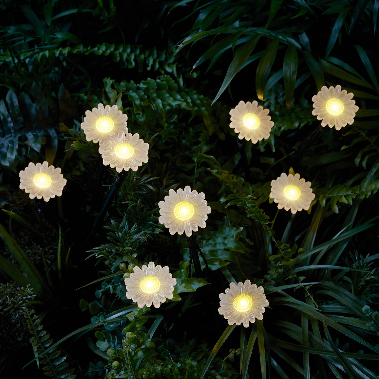 Des Balises Solaires en forme de Pâquerettes installées  au milieur de la végétation dans le jardin. 