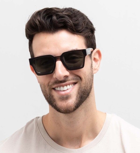 man wearing Noir, oversized geometric sunglasses with green lenses, on a white background